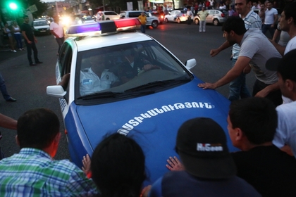 Жители Еревана перед полицейской машиной у захваченного здания