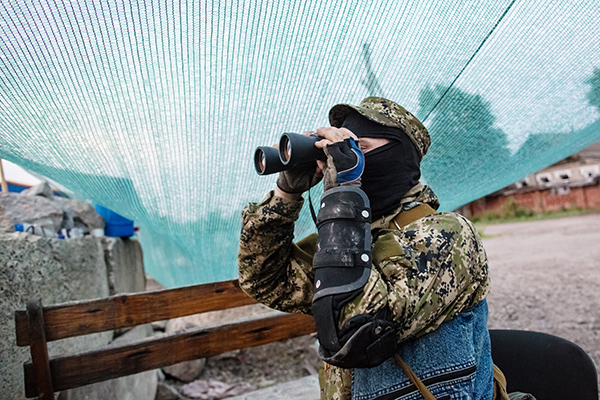Боец народного ополчения Донбасса наблюдает за передвижением украинских военных 