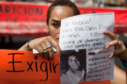 Женщина держит плакат с изображением одного из похищенных