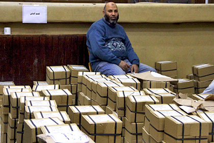 Египтянин сидит на упаковках с бланками для голосования