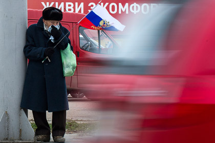 Пожилой мужчина с российским флагом на улице Севастополя